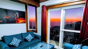 Sala de estar con sofá, mesa de centro, ventilador de techo y un ventanal con cortinas.