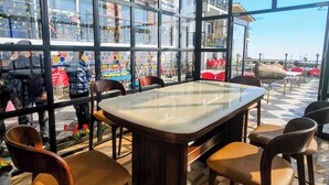 Un restaurante con zona de comedor cubierta por vidrio, suelo de madera y vista a la calle.