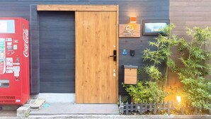 Un edificio moderno con una puerta de madera, una máquina expendedora de Coca-Cola y un pequeño letrero que indica la habitación número 39-10.