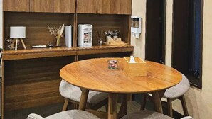 Una cocina compacta con armarios de madera, una mesa redonda con cuatro sillas y un reloj en la pared.