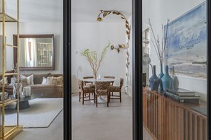 Una sala de estar moderna con comedor, un espejo grande y un cuadro en la pared.
