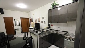 Cocina compacta con comedor, que incluye estufa, lavabo, armarios y una pequeña mesa con sillas.