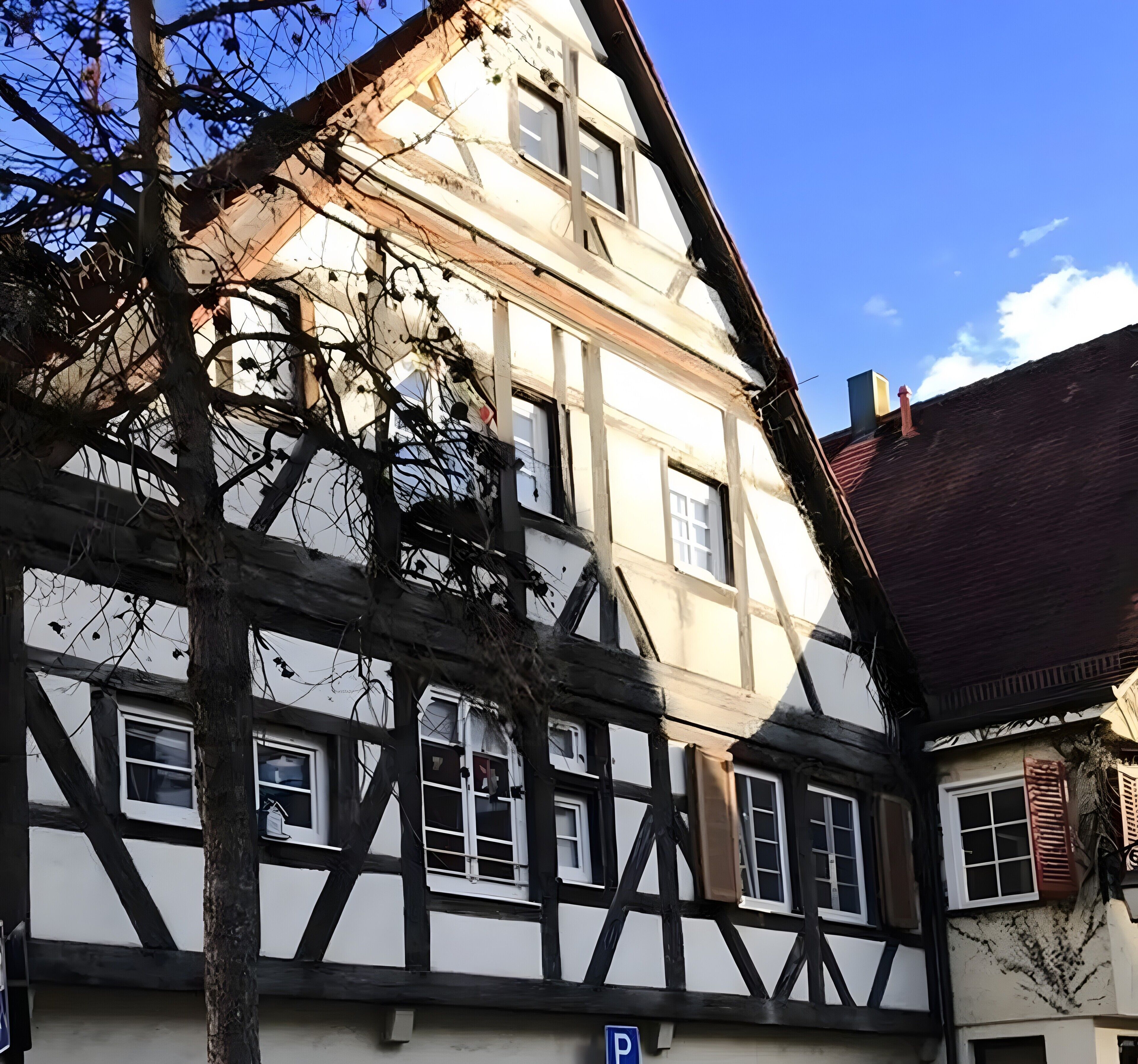 Ein traditionelles Fachwerkhäuschen mit mehreren Fenstern und einem sichtbaren Parkplatzschild.
