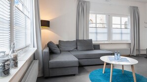 Ein modernes Wohnzimmer mit einem grauen Sofa, einem runden Couchtisch und einem blauen Teppich.