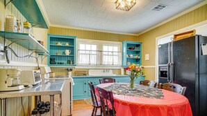 A kitchen with teal cabinets, a black refrigerator, and a dining table with a red tablecloth. - Walkable Dtwn Lafayette Home w/ Screened Porch (Lafayette)