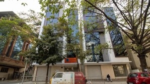 Un edificio con fachada moderna, una furgoneta estacionada y un árbol en primer plano.