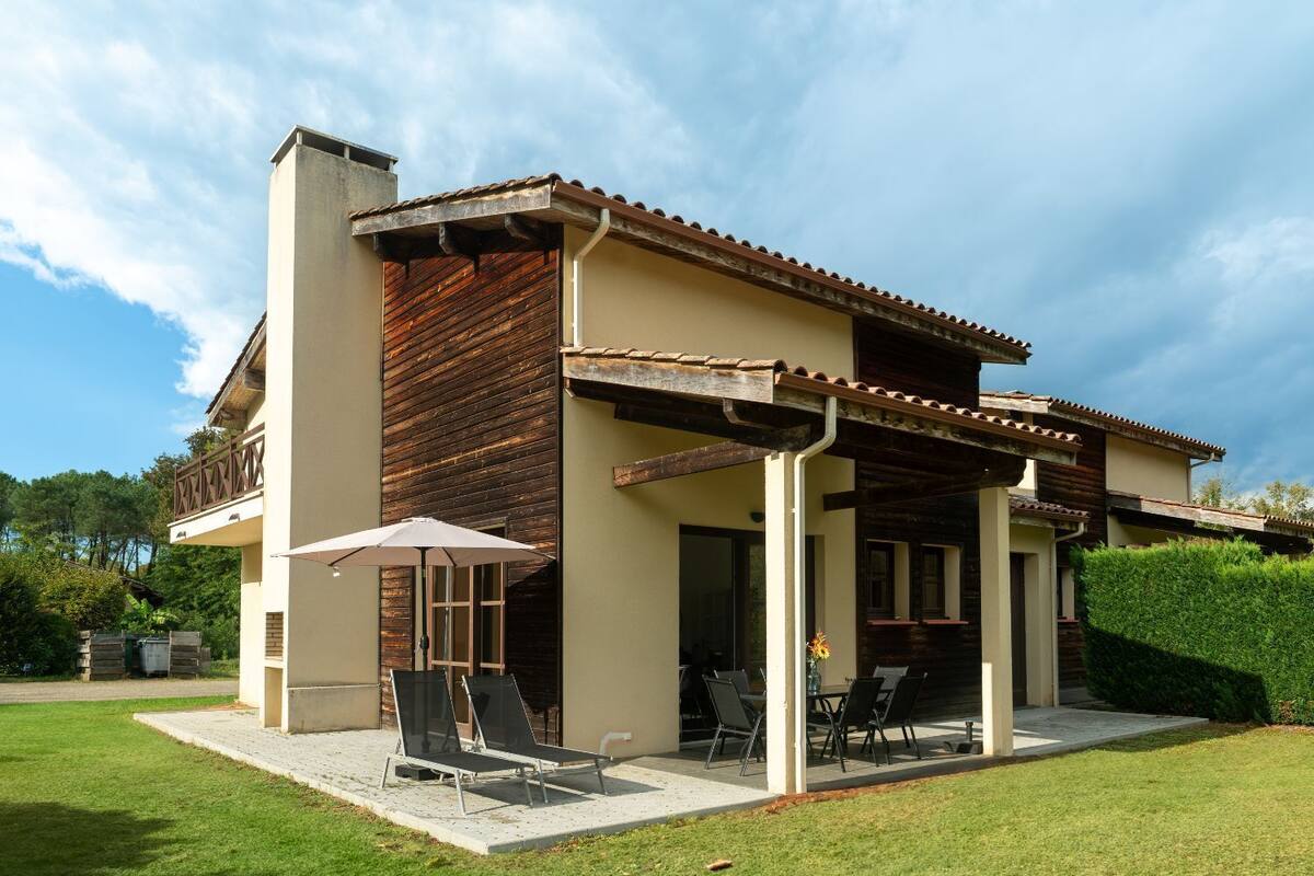 A two-story house with a patio, a covered outdoor seating area, and a large window.