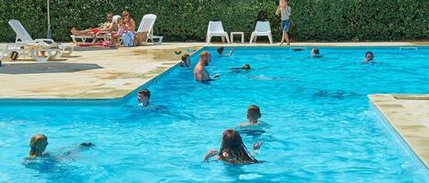 Una piscina al aire libre de temporada, sillones reclinables de piscina