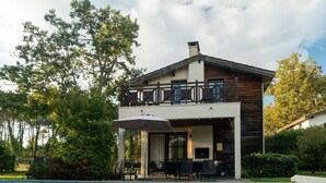 Una casa a due piani con piscina, area salotto esterna e terrazza in legno.