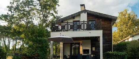 Ein zweigeschossiges Haus mit Pool, Sitzgelegenheit im Freien und einer Holzterrasse.