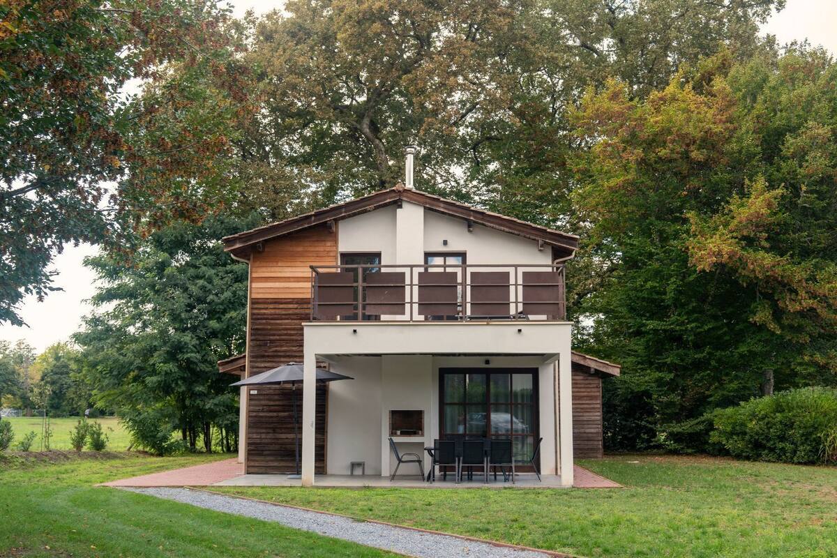 A two-story house with a balcony, a covered patio, and a large window.