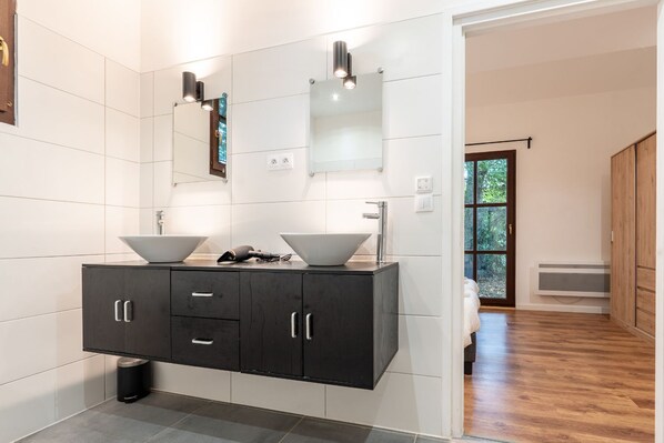 Un baño moderno con tocador doble, un espejo grande y vistas de un suelo de madera y un ventanal.