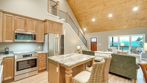 A spacious kitchen with modern appliances, a dining area with a marble table, and a cozy seating area with wicker chairs. - Modern Cabin w/ Sweeping Views in Blue Ridge Mtns! (Green Mountain)