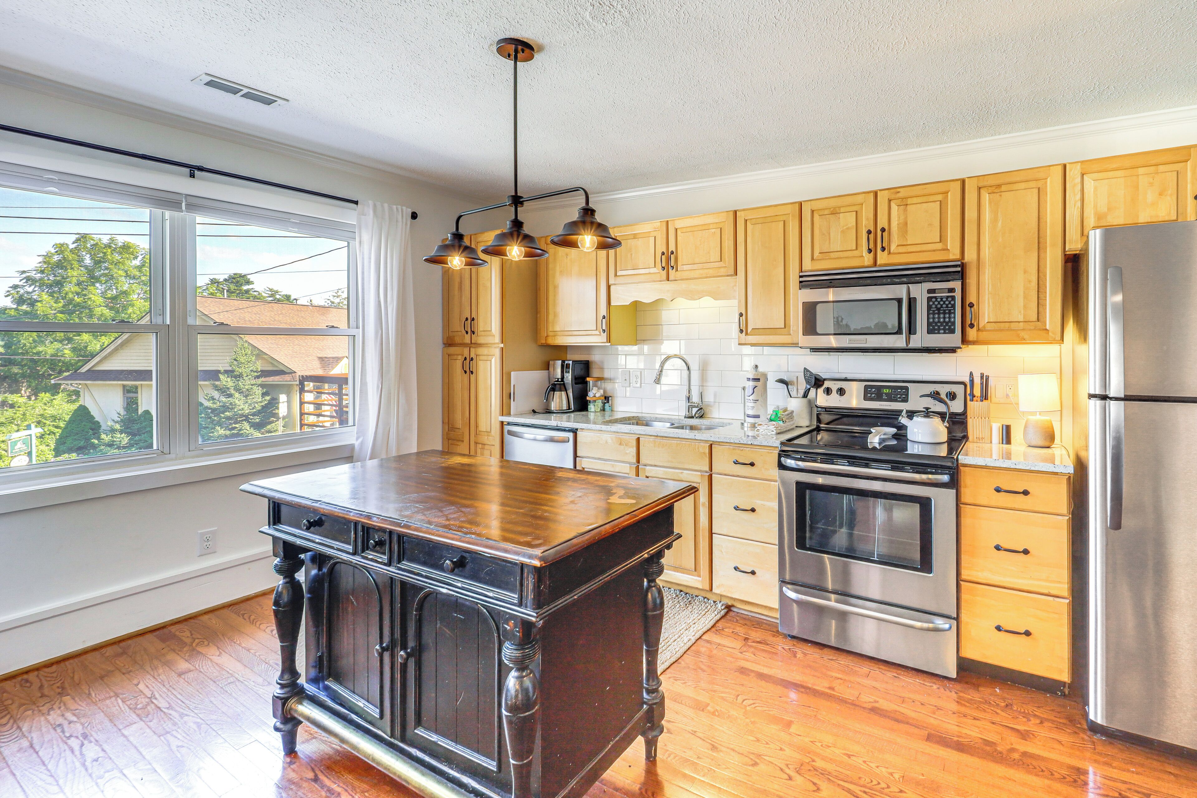 A kitchen with wooden cabinets, a stainless steel refrigerator, a microwave, and a stove.