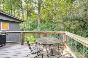 A wooden deck with a metal table and chairs, surrounded by a metal fence and dense greenery. - Walk to Shops, Eats & Trails: Blowing Rock Escape! (Blowing Rock)