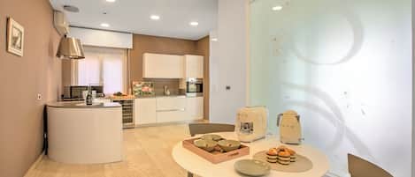 A modern kitchen with white cabinets, a central island, and a dining area with a round table and chairs.