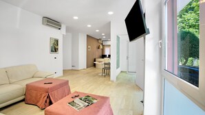 Ein modernes Wohnzimmer mit einer Couch, einem Hocker und einem an der Wand befestigten Flachbildfernseher.