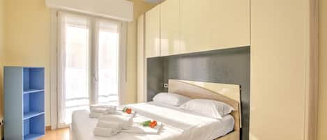 A bedroom with a bed, a wardrobe, and a blue shelving unit.