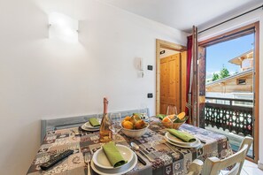 A dining table set with plates, glasses, and a bowl of fruit. - Baita Menin Apartments (Livigno)