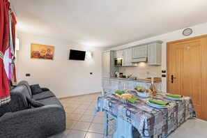 A compact living space with a dining area, kitchenette, and a sofa. - Baita Menin Apartments (Livigno)
