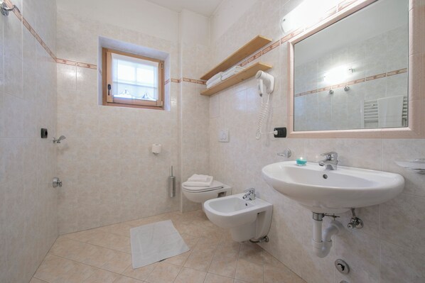 A bathroom with a bidet, a sink, a mirror, and a window. - Baita Menin Apartments (Livigno)