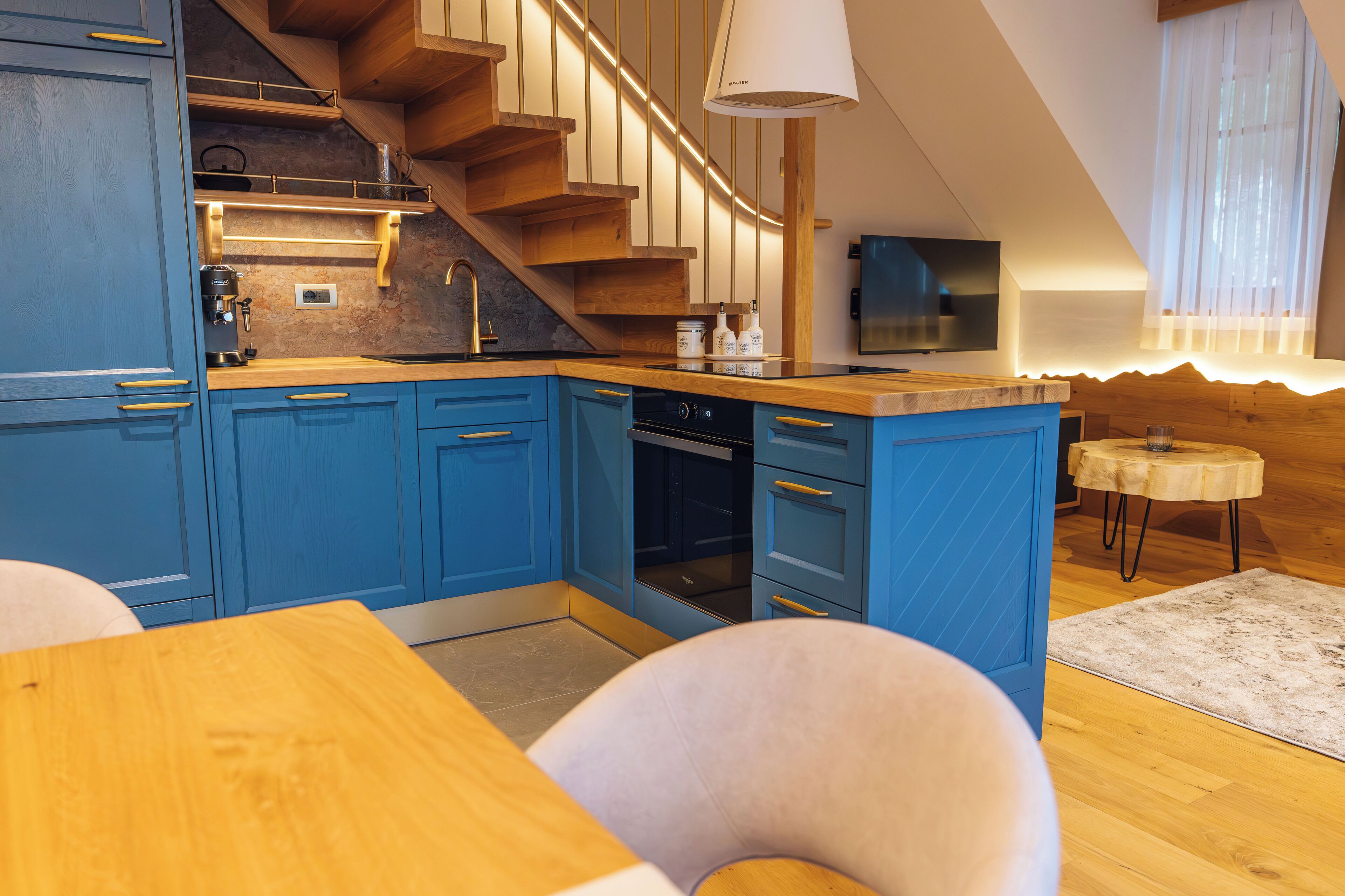 A modern kitchen with blue cabinets, wooden countertops, and a built-in oven.