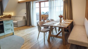 Una sala de estar moderna con comedor, piso de madera y un ventanal con cortinas.