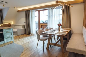 Una sala de estar moderna con comedor, piso de madera y un ventanal con cortinas.