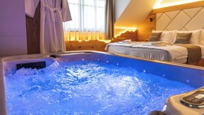 Habitación de hotel con bañera de hidromasaje, una cama con almohadas y una bata colgada en la pared.