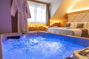 Habitación de hotel con bañera de hidromasaje, una cama con almohadas y una bata colgada en la pared.