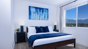 A bedroom with a bed, two bedside tables, a nightstand, a window with a view, and a painting on the wall. - Sugarhouse-1BR 1BA Great Views! (Salt Lake City)