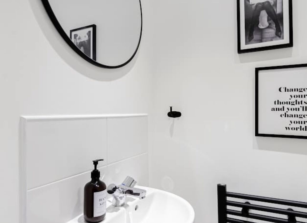 A bathroom with a white sink, a mirror, and a framed quote on the wall.