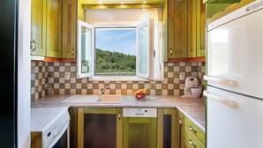 Una cocina compacta con ventana, un lavamanos, lavavajillas y refrigerador.