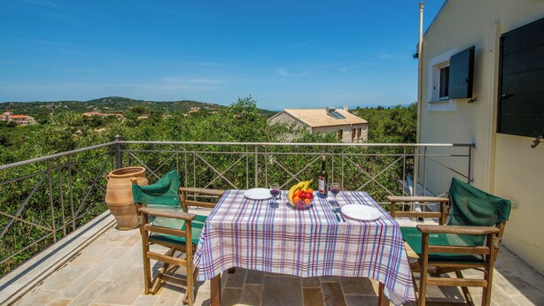 Un espacio de comedor al aire libre con una mesa preparada para dos personas, rodeada de sillas, con vistas a un paisaje pintoresco.