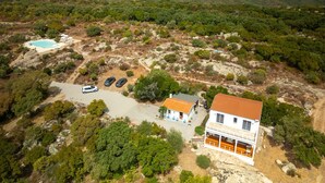 A coastal property with a swimming pool, parked cars, and a building with a red roof.