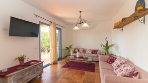 A living room with a sofa, coffee table, TV, and decorative plants.