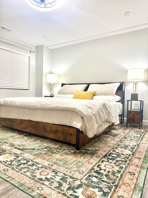 A bedroom with a bed, nightstands, a floor lamp, and a patterned rug.