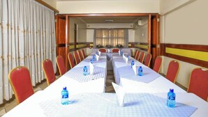 A conference room with long tables, red chairs, and water bottles on the tables. - Paris Hotel (Nairobi)