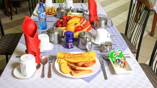 A breakfast table set with various dishes, utensils, and condiments. - Paris Hotel (Nairobi)