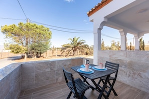 A balcony with a table and chairs, a tiled floor, and a view of trees and a palm tree. - Apartment 'La Palmera' with Private Terrace and Air Conditioning (El Nazareno)