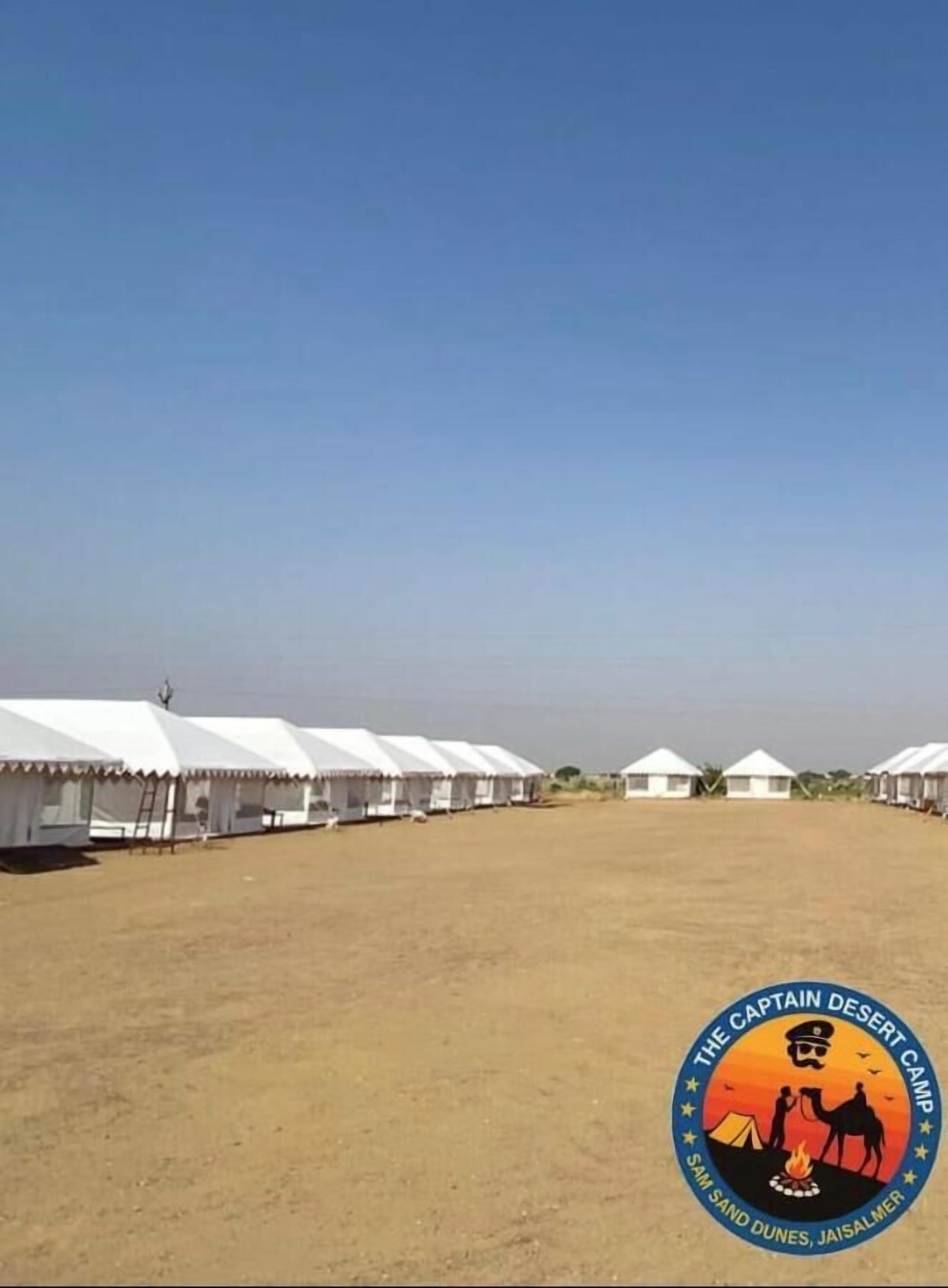A sandy area with tents and a logo for "The Captain Desert Camp".