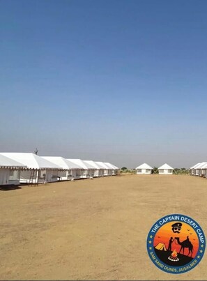 A sandy area with tents and a logo for "The Captain Desert Camp". - The Captain Desert Camp (Jaisalmer)