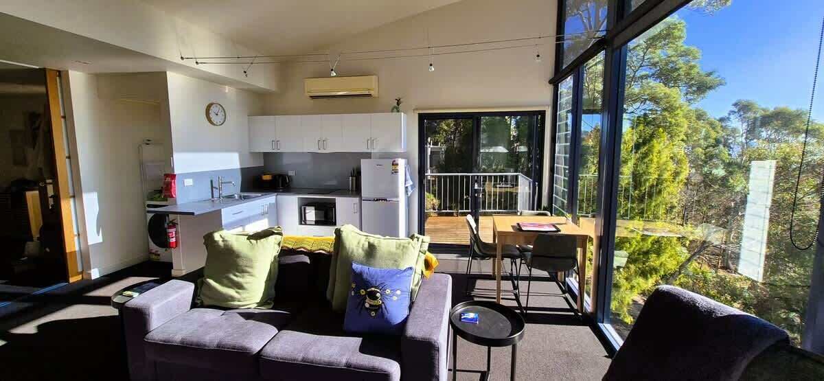 A modern living space with a sofa, a dining table, and a kitchen area.