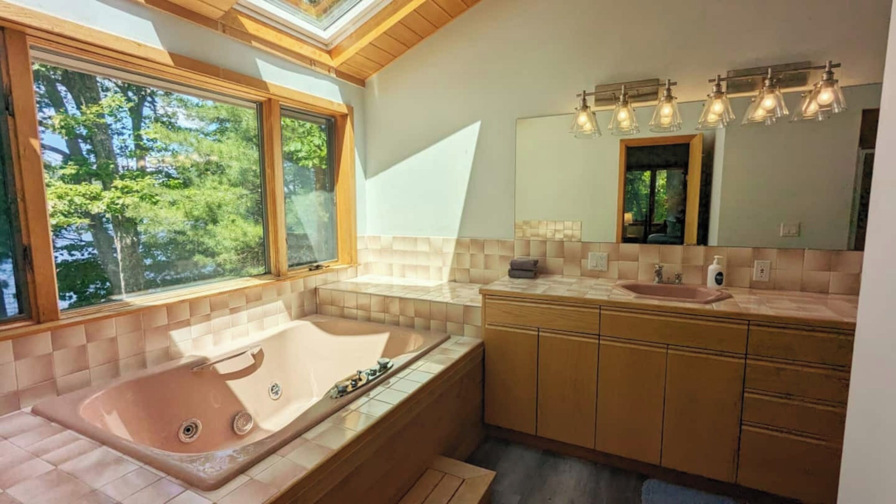 Ein modernes Badezimmer mit einer großen Badewanne, einem Waschtisch und einem großen Spiegel.