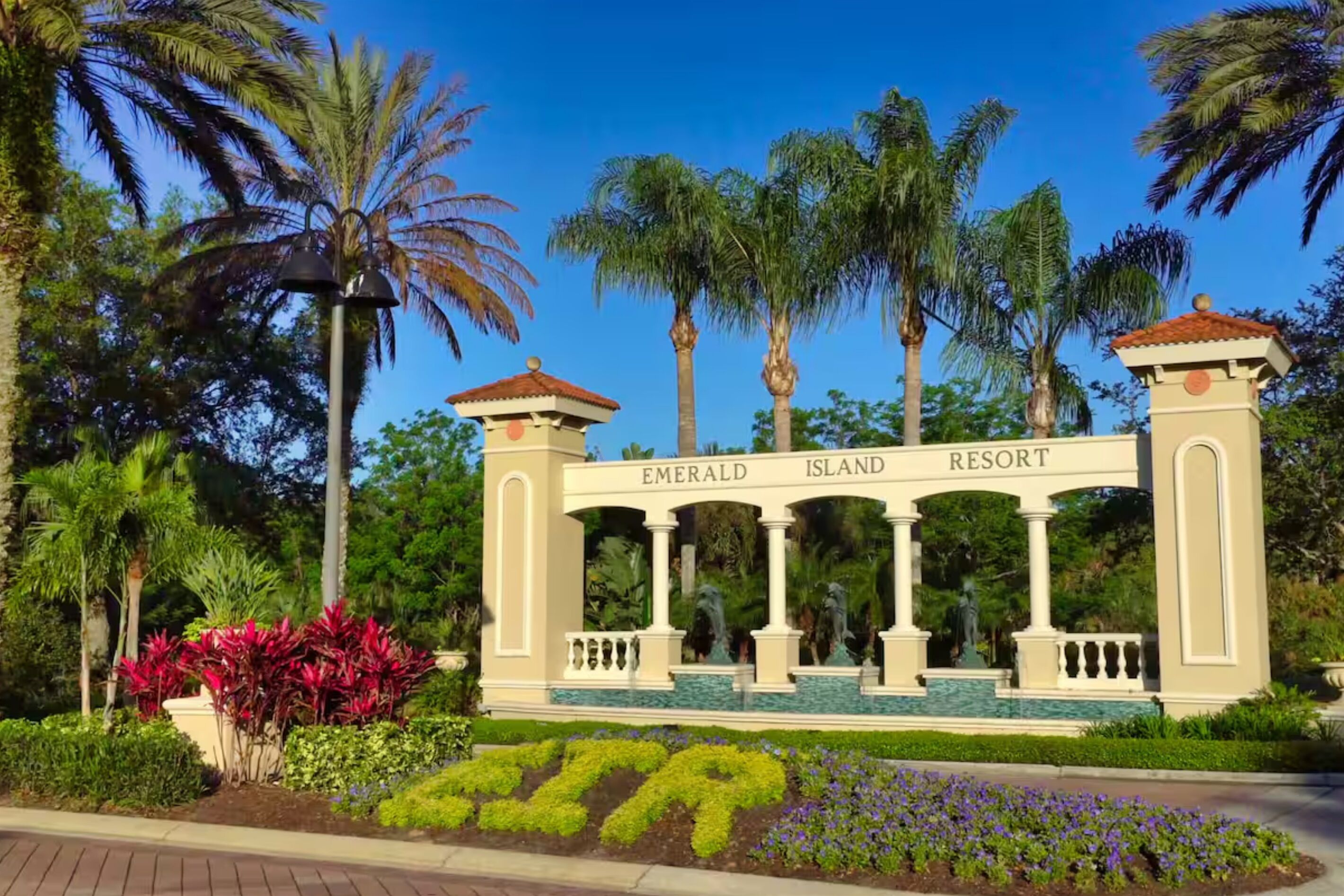 A sign for Emerald Island Resort with a classical architectural style, featuring columns and a decorative entrance.