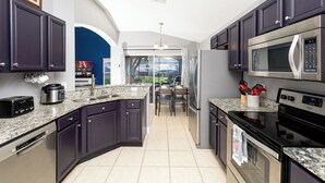A modern kitchen with dark cabinets, stainless steel appliances, and a granite countertop. - 5BRDisney Villa w/ Pool,Game Room & Resort Access (Kisimmee)