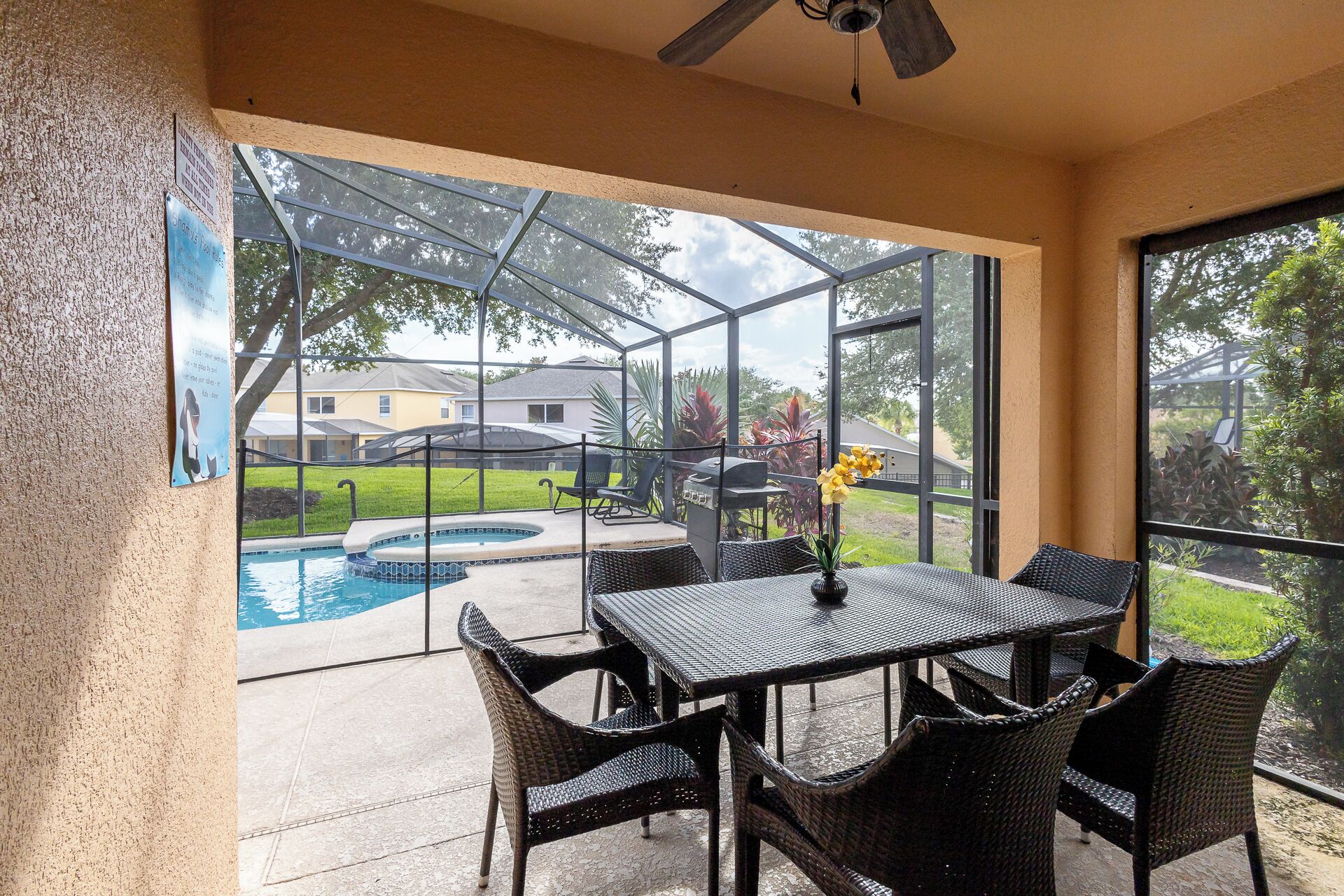 A covered patio area with a pool, outdoor seating, and a view of the neighborhood.