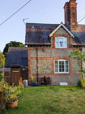 A rustic cottage with a stone facade, a wooden door labeled "Crumble Cottage," and a small garden with a bench and potted plants. - Country cottage.
Perfect quiet retreat, away from the hustle and bustle of life. (Motcombe)