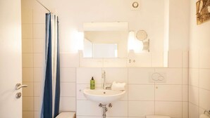 Ein Badezimmer mit Dusche, Waschbecken, Toilette und einem Spiegel über dem Waschbecken.