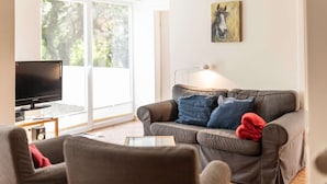A living room with a grey sofa, a television, and a painting on the wall.